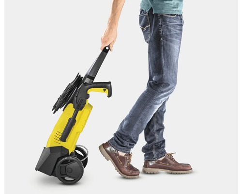 Une personne tire un nettoyeur haute pression jaune.