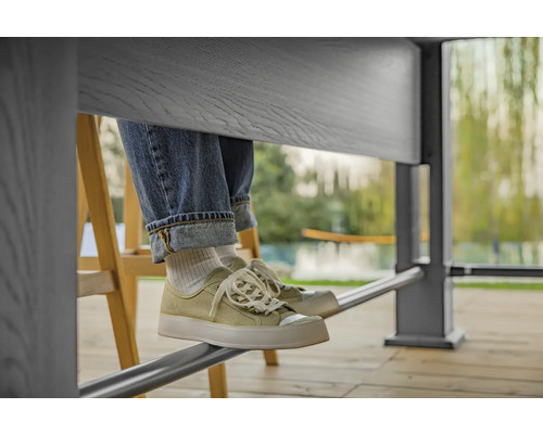 Person sitzt am Tisch mit Jeans und Turnschuhen