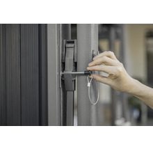 Detailansicht eines Tors mit einem Verschlussmechanismus und einer Person, die diesen betätigt