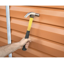 Hand hält Hammer, um einen Nagel in eine Wand zu schlagen