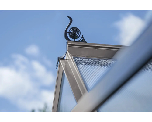 Detailansicht eines Gewächshausdachs mit dekorativem Firstaufsatz vor blauem Himmel