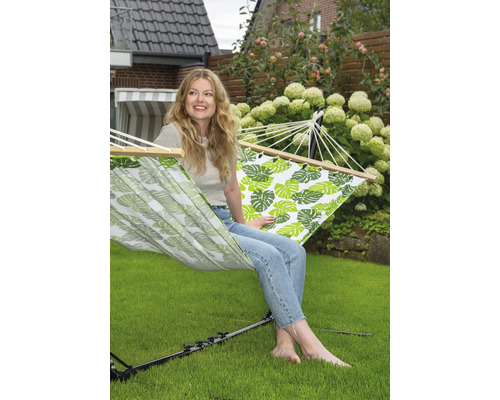 Femme se détend dans un hamac à motifs de feuilles dans le jardin