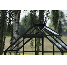 Detailansicht eines Gewächshauses aus Glas und Metall im Garten.