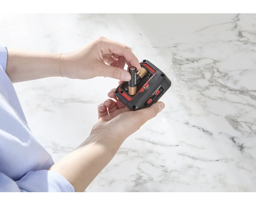 Une personne insère des piles dans un appareil électronique