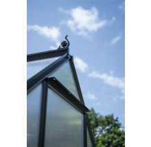 Detailansicht eines Gewächshauses mit dekorativer Dachspitze vor blauem Himmel