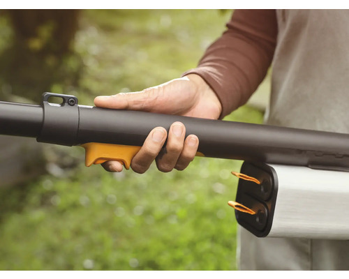 Une personne tient un souffleur de feuilles dans sa main.