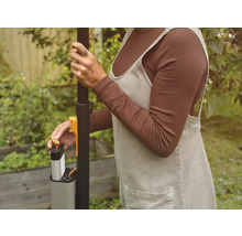 Une personne insère une batterie dans un outil de jardinage.