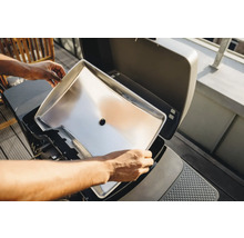 Une plaque de cuisson en acier inoxydable est insérée dans un grill.