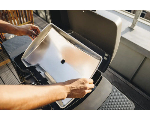 Une plaque de cuisson en acier inoxydable est insérée dans un grill.