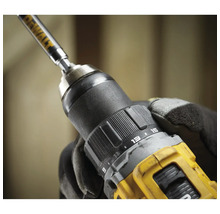 Nahaufnahme einer Bohrmaschine mit eingesetztem Bohrer, gehalten von einer Hand mit Arbeitshandschuh