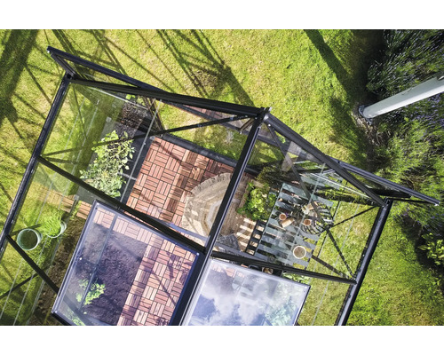 Vue de dessus d'une serre avec des plantes et des outils de jardin sur une pelouse