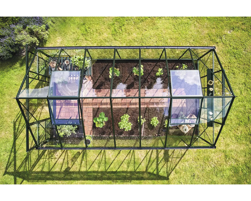 Vue de dessus d'une serre avec des plantes et un sol carrelé sur une pelouse verte.