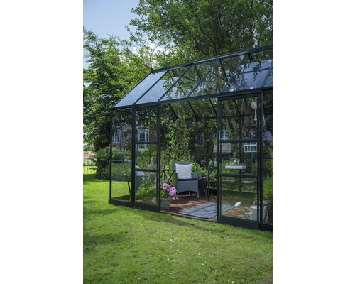 Serre avec plantes, chaise et accessoires de jardin dans le jardin