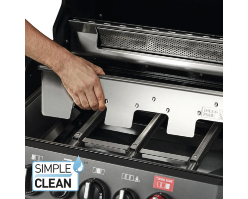 Une main place une plaque en acier inoxydable dans un barbecue.