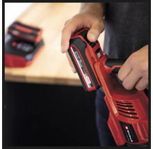 Une personne tient un outil sans fil rouge Einhell avec une batterie insérée.