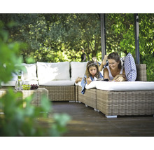 Mutter und Tochter entspannen auf einem Rattansofa im Garten unter einem Pavillon.