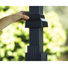 Main installant un capuchon de poteau noir sur un poteau de clôture