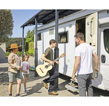 Famille avec guitare sous un toit de terrasse à côté d'un camping-car