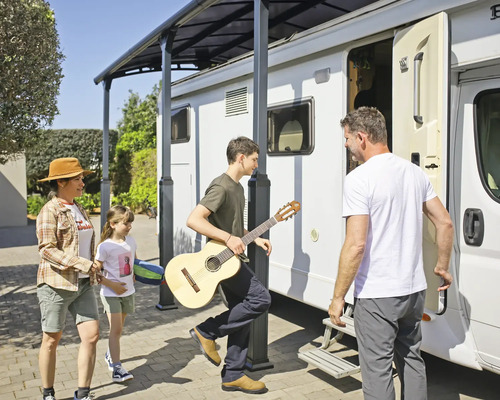 Famille avec guitare sous un toit de terrasse à côté d'un camping-car