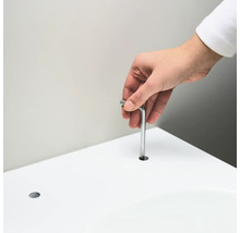 Une personne insère une clé Allen dans un trou dans une surface blanche