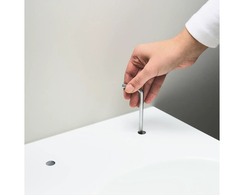 Une personne insère une clé Allen dans un trou dans une surface blanche