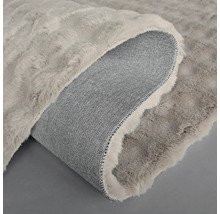 Vue détaillée d'un tapis à l'aspect fourrure avec un dos tissé