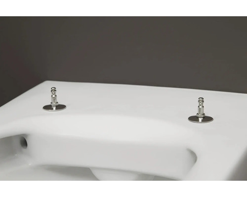 Nahaufnahme einer weißen Toilette mit silberfarbenen Befestigungen für den Toilettensitz