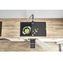 Küchenspüle mit Abtropffläche, Armatur, Gemüsesieb und Abfallbehälter in einem modernen Küchendesign.