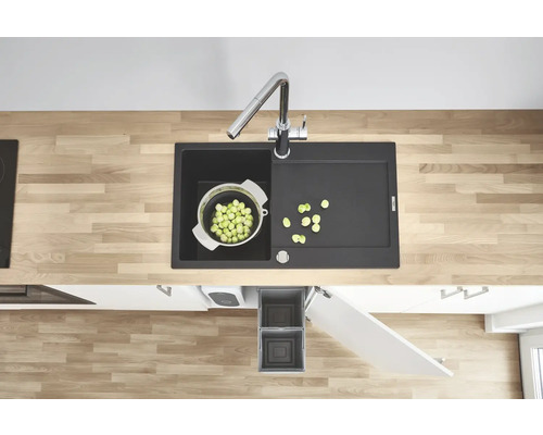 Küchenspüle mit Abtropffläche, Armatur, Gemüsesieb und Abfallbehälter in einem modernen Küchendesign.