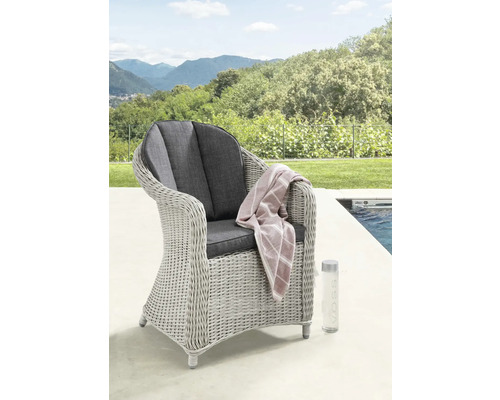 Fauteuil de jardin en rotin avec coussin et serviette à côté de la piscine