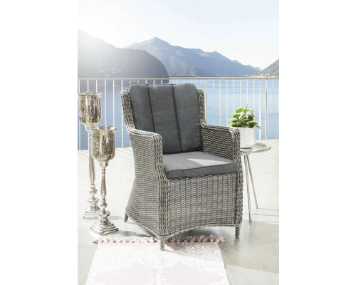 Fauteuil de jardin avec coussins gris, table d'appoint et bougeoir sur une terrasse avec vue sur le lac