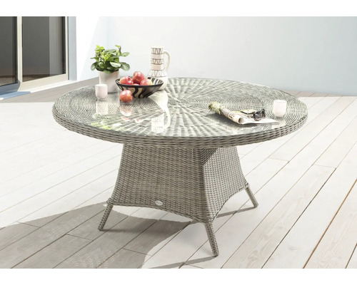 Table de jardin ronde avec plateau en verre, structure en rotin et décoration