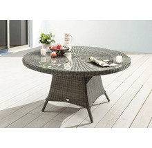 Table de jardin ronde avec plateau en verre et aspect rotin sur une terrasse.