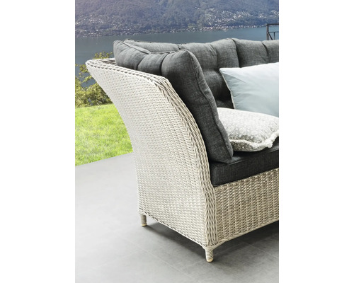 Vue détaillée d'une chaise en rotin avec des coussins gris et vue sur un paysage pittoresque.
