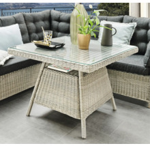 Table de jardin avec plateau en verre et structure en rotin, faisant partie d'un ensemble de salon d'extérieur
