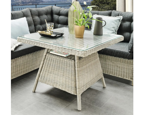 Table de jardin avec plateau en verre et structure en rotin, faisant partie d'un ensemble de salon d'extérieur