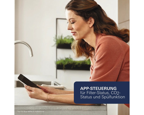Eine Frau benutzt ein Tablet in der Küche zur App Steuerung von Filterstatus, Kohlenstoffdioxyd Status und Spülfunktion.