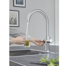 Une personne fait couler de l'eau d'un robinet dans un verre pour préparer du thé.