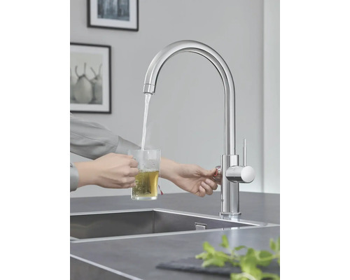 Une personne fait couler de l'eau d'un robinet dans un verre pour préparer du thé.