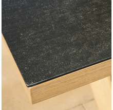 Gros plan sur un coin de table avec une surface sombre à l'aspect pierre et un cadre en décor bois clair.