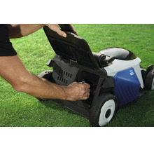 Ein Mann entleert den Fangkorb eines Rasenmähers auf einer Rasenfläche.