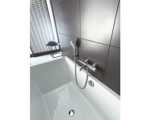 Salle de bains avec baignoire blanche et robinetterie avec douchette devant un mur gris