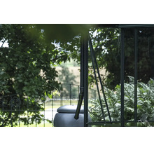 Récupérateur d'eau de pluie sur une serre avec des arbres en arrière-plan