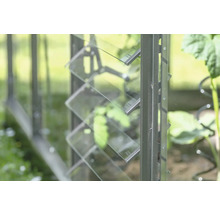 Vue détaillée d'une serre avec fenêtre à lamelles en verre pour la ventilation.