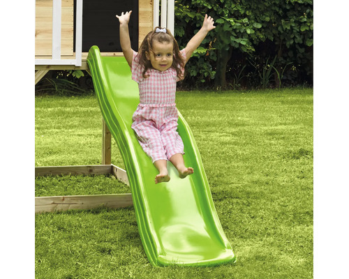 Fille glissant sur un toboggan vert pour enfants dans le jardin