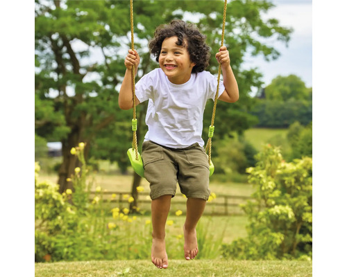Garçon souriant sur balançoire de jardin