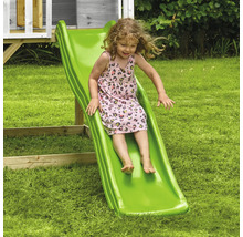 Fille glissant sur un toboggan vert dans le jardin
