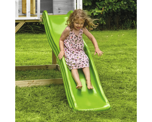 Fille glissant sur un toboggan vert dans le jardin