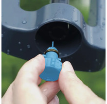 Gros plan d'une main insérant une buse dans un arroseur de pelouse.