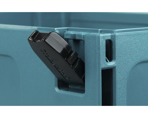 Gros plan d'un fermoir en plastique noir sur une mallette à outils Makita.